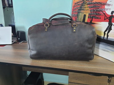 Custom made unisex duffle bag made from dark brown leather within custom made realization