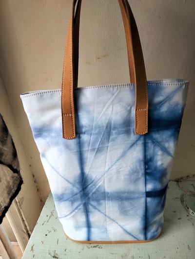 Custom made tie-dye fabric bag with brown leather straps within custom made realization