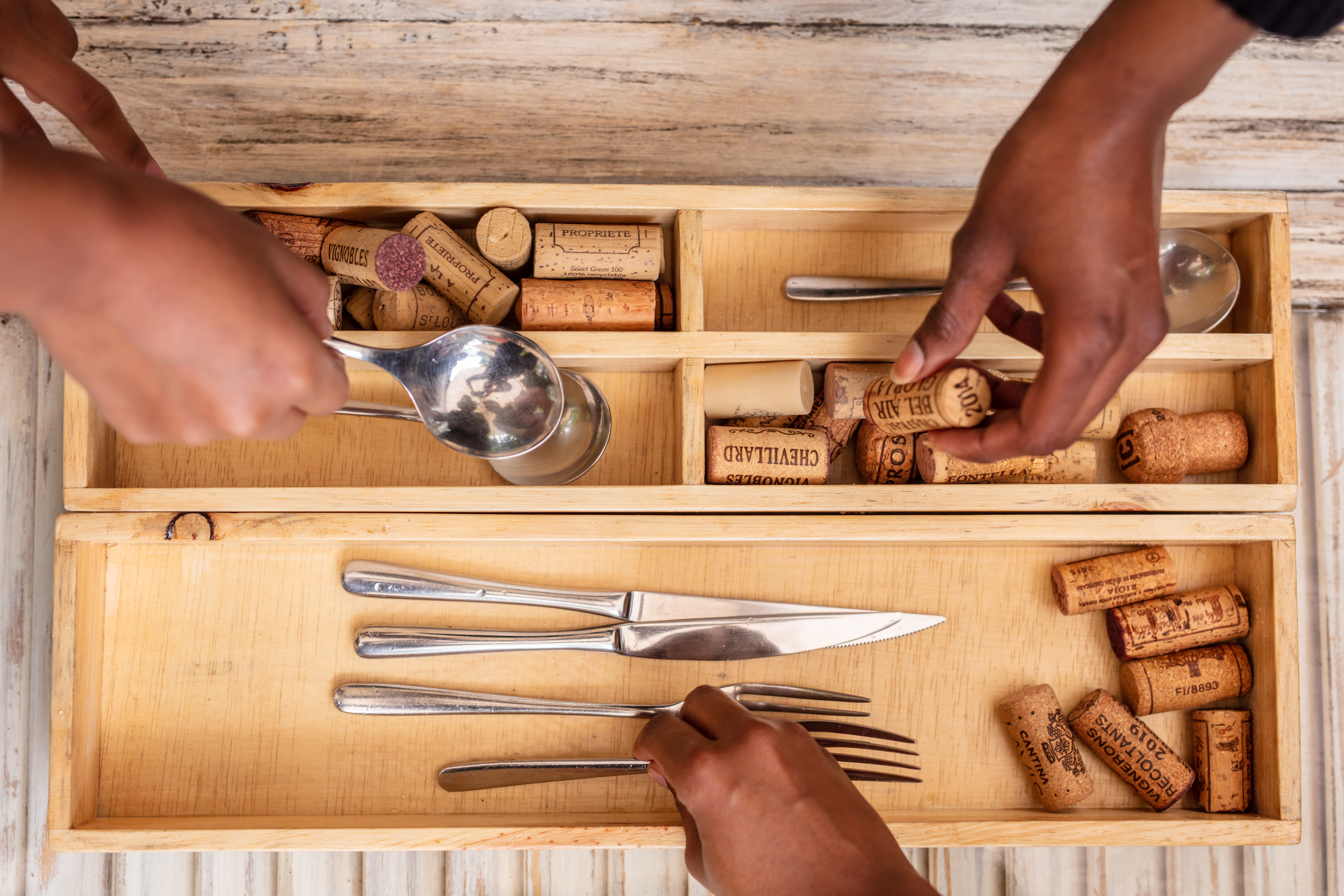 An image of a wooden cutlery tray made by an Urban Change Lab artisan. The image is demonstrating the use of the custom-made tray.